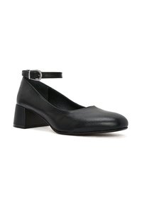 Zapatos de tacón de cuero negro con punta redondeada, correa en el tobillo y un tacón de bloque geométrico. Textura suave y diseño minimalista.