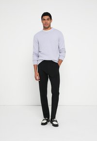 Pulover tricotat ușor lavandă, cu gât rotund, asortat cu pantaloni negri croiți și pantofi eleganți alb-negru.