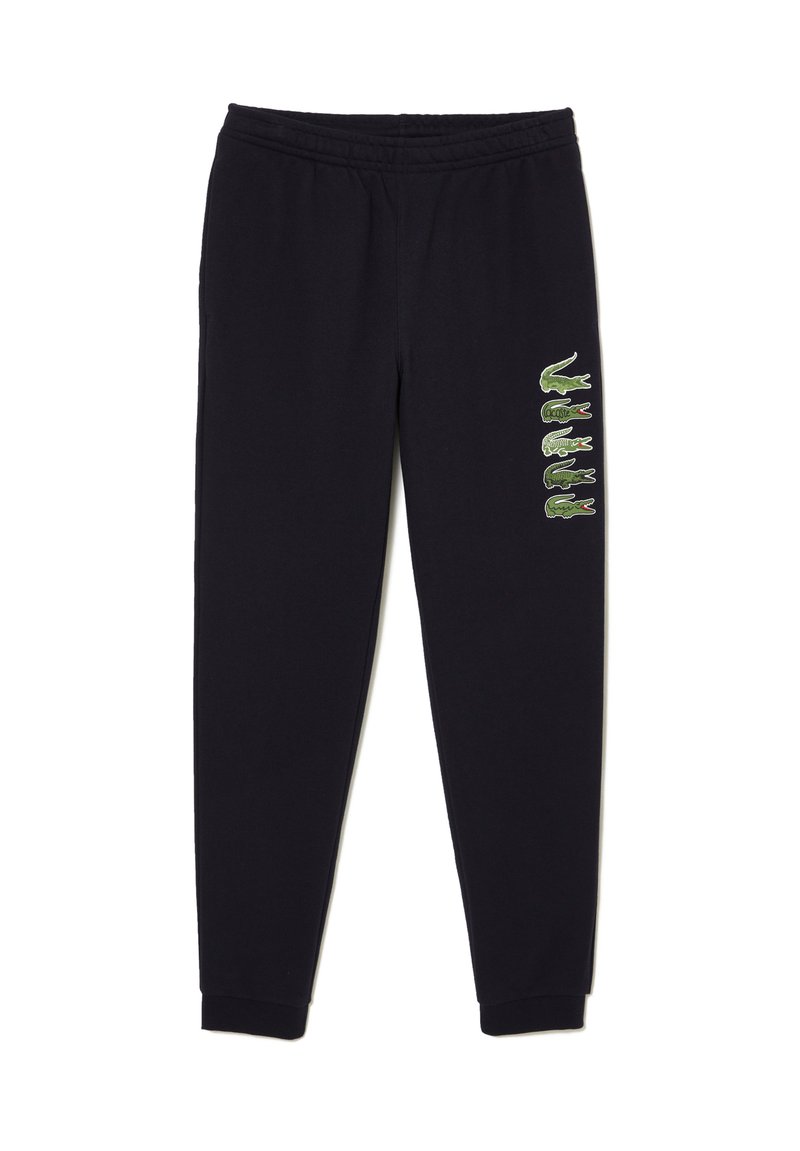 Pantalons de survêtement noirs en tissu doux, avec une taille à côtes et des poignets aux chevilles, dotés de logos de crocodile verts le long du côté gauche.