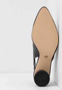 Semelle de chaussure noire à bout pointu avec talon antidérapant, dessous beige, et marquage taille 37 visible sur fond blanc.