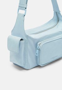 Lichtblauwe synthetische handtas met meerdere ritscompartimenten, verstelbare schouderband en een klein zijvak. Gladde textuur met een minimalistisch ontwerp.