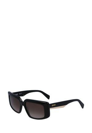 Lunettes de soleil noires surdimensionnées avec des verres dégradés bruns, dotées de branches texturées accentuées de doré. Le design est carré avec une finition brillante.