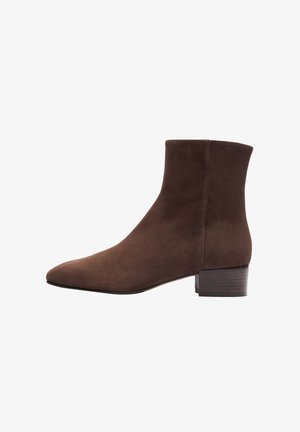 Bottine en suede marron avec un bout pointu, finition lisse et un petit talon carré. Présente un design minimaliste sans quincaillerie visible.