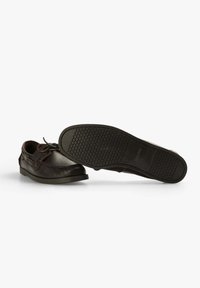 Schwarze Lederschuhe mit runder Zehenform, dünnen Schnürsenkeln, strukturierten Oberflächen und Gummilaufsohle mit einem Profilmuster.