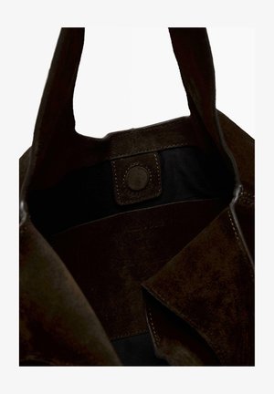 Brown suede tote bag interior featuring a black lining, snap button closure, and subtle branding embossed on the inside panel.