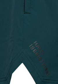 Mörk teal shorts av lättviktsmaterial, med en diagonal söm och präglad detalj "HALO 1968/1972/1981" på vänster sida.