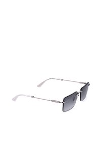 Lunettes de soleil à monture rectangulaire avec fines branches en métal argenté et verres teintés foncés, inclinées vers la droite sur un fond blanc.