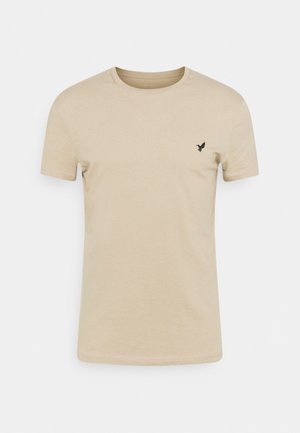 Beige short-sleeve T-shirt made of soft fabric, featuring a round neckline and a small black bird logo on the left chest area.