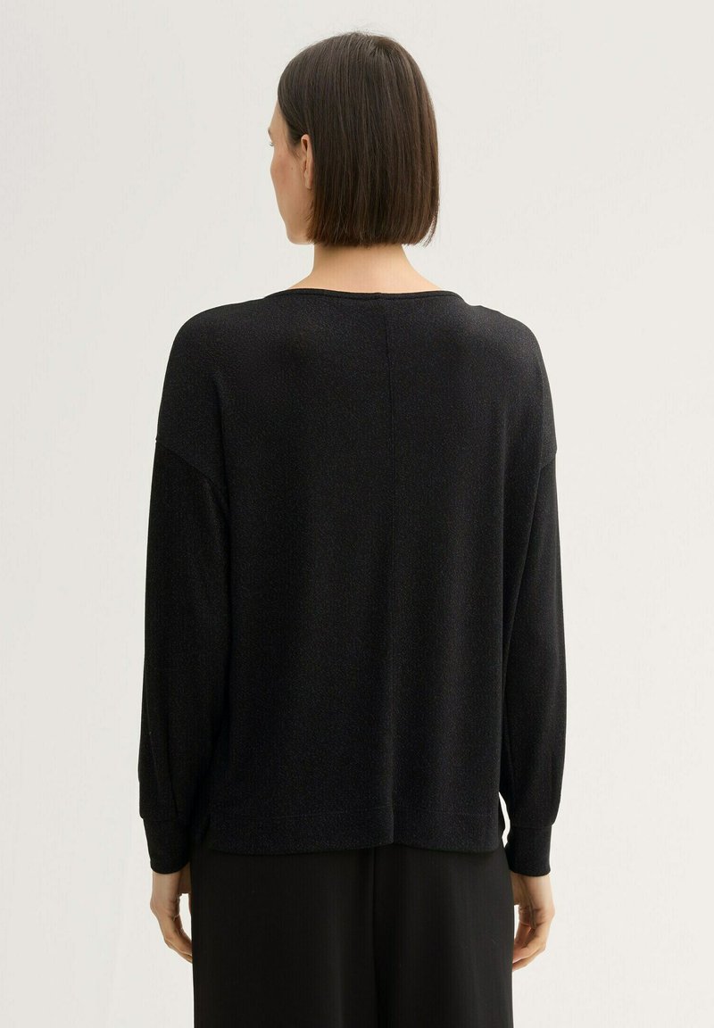 Maglione nero a collo rotondo con vestibilità ampia, spalle basse e polsini a coste. Tessuto morbido con leggera lucentezza, progettato per il comfort e per essere stratificato.