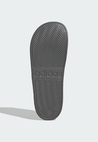 Black rubber sneaker sole featuring a herringbone pattern, with “adidas” embossed on the side and rounded edges.