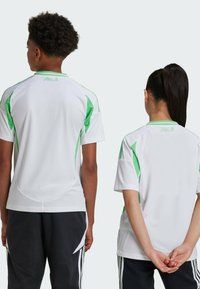 Witte sportshirts met groene accenten, korte mouwen en meshdetails, weergegeven vanaf de achterkant op twee figuren.
