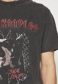 Czarna bawełniana koszulka z grafikiem przedstawiającym wilka oraz napisem "KOOPLE" na czerwono i "BACK TO LIFE" na białym, na postarzonym tle.