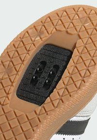 Podeszwa buta z teksturowanym wzorem z gumy, z czarną strefą do przymocowania oraz białą skórzaną cholewką z szarym akcentem.