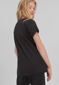 Zwarte katoen t-shirt met korte mouwen, klassieke snit, zachte textuur en een rechte zoom. Heeft een minimalistisch ontwerp, zonder patronen of accenten.