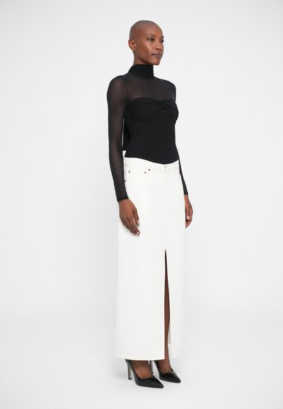Sort langærmet tætsiddende bodystocking med rynket forside, parret med en hvid denimnederdel med højt slid. Sorte spidse højhælede sko fuldender outfittet.