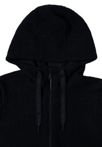 Haut à capuche en polaire noire avec une surface texturée, fermeture éclair et cordons contrastants portant le texte "FAIS TON PROPRE CHEMIN."