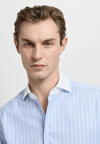 Svetlo modra srajca z navpičnimi črtami, belim ovratnikom, zapenjanjem na gumbe in gladko teksturo tkanine, s krojem po meri.