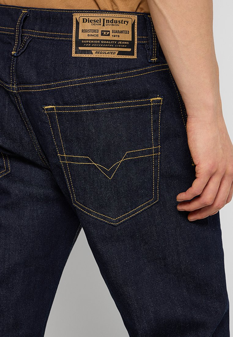 Dunkelblaue Jeans mit strukturierter Oberfläche. Ausgestattet mit goldenen Nähten, einem markierten Lederpatch und einem auffälligen Taschendesign.