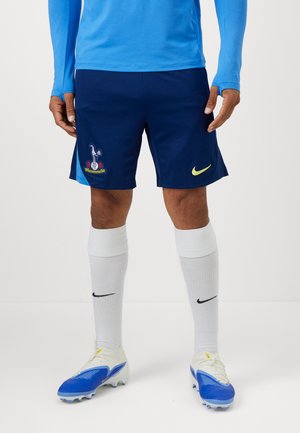 Mørkeblå atletikshorts med broderet klublogo, matchende blå stribet design og gul Nike swoosh accent. Hvide sportsstrømper.