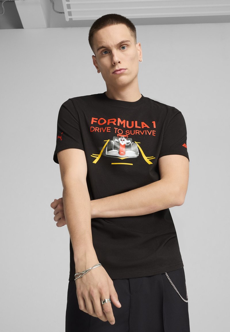 Musta puuvillapaita, jossa on punainen ja keltainen "Formula 1 Drive to Survive" -grafiikka, lyhyet hihat ja Puma-logo olkapäällä.