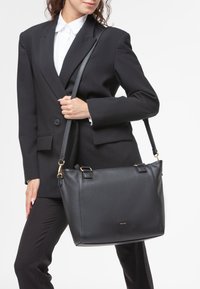Borsa a spalla in pelle nera con finitura testurizzata, hardware dorato e due manici superiori. Adatta per ambienti professionali.