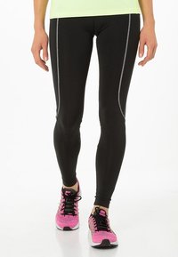 Leggings atléticos negros con costuras en gris contrastante, combinados con zapatillas de correr rosa y negras, que cuentan con una parte superior de malla transpirable.