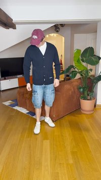 Cardigã azul-marinho com um padrão texturizado, fecho de botão e detalhe de marca, combinado com calções de carga azul-claro e ténis brancos.