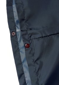 Námořnicky modrá nylonová tkanina s hladkou texturou obsahuje dva tmavě červené knoflíky a kontrastní světle modrý šev podél okraje.