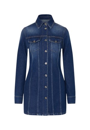 Vrouw poseert in een donkerblauwe denimjurk met knopen, lange mouwen en zilveren sandalen met hoge hak tegen een effen achtergrond.