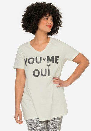 T-shirt blanc à manches courtes et col en V avec "YOU♥ME OUI" imprimé en lettres noires. Matière en coton doux, coupe décontractée, associé à un pantalon à motifs.