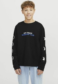 Sudadera negra de manga larga con "CLUB DE MIEMBROS FUERA DE RUTA" en letras azules, con gráficos de estrellas y círculos blancos en las mangas.