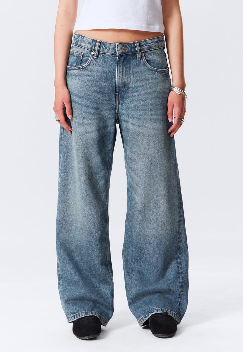 Jean large bleu clair en denim, avec un effet décoloré, un design à cinq poches et une fermeture par bouton à la taille.