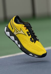 Chaussure de sport Nike avec un dessus jaune vif, un système de laçage noir, des détails texturés et une semelle rembourrée noire et blanche.