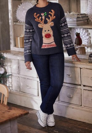 Dunkelgrauer gestrickter Pullover mit Rentiermotiv, glitzernden Geweihen, roter Nase und gemusterten Ärmeln, kombiniert mit blauen Jeans und weißen Turnschuhen.