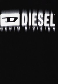 Črna majica s kratkimi rokavi z logotipom "DIESEL" in besedilom "DENIM DIVISION" v velikem, belim gradientnim tiskom. Mehka bombažna tkanina z gladko teksturo.