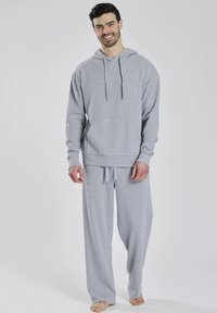 Grå hættetrøje og matchende sweatpants lavet af blødt bomuldsblandingsstof. Hættetrøjen har en kengurulomme og justerbare snore.