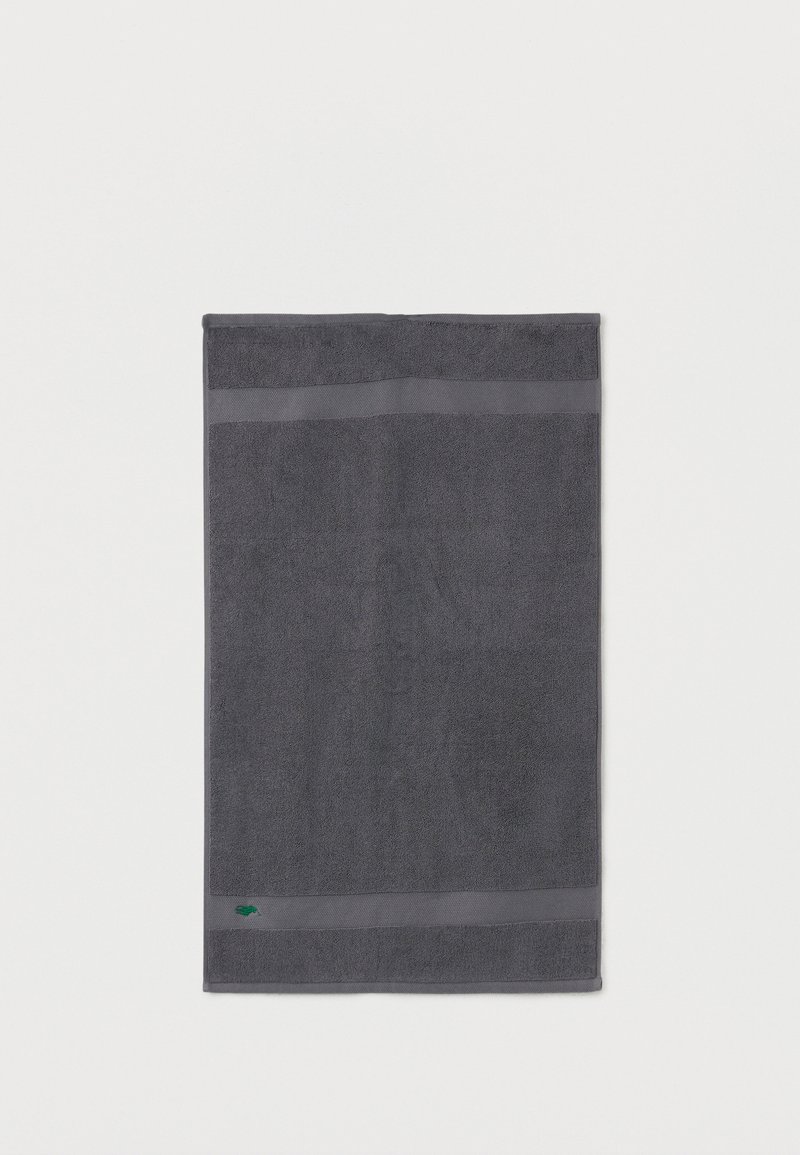 Σκοτεινό γκρι ορθογώνιο πετσέτα με υφή ρίγας κοντά στις άκρες και μικρό πράσινο λογότυπο κοντά στην κάτω αριστερή γωνία.