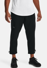 Pantaloni sportivi neri con vestibilità affusolata, polsini elastici e una superficie liscia. Presentano cuciture visibili e un logo discreto sulla coscia.