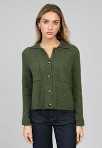 Cardigan vert en mélange de laine avec un col, une fermeture à boutons sur le devant, deux poches poitrine et des poignets côtelés ; texture douce et coupe décontractée.