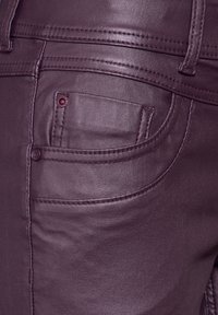 Mörkröda kostymbyxor i konstläder med slät textur, med en liten ficka och dekorativ sömnad. Inkluderar en detalj med knappstängning.