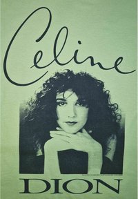 Zelené tričko s černou grafikou ženy s kudrnatými vlasy, rukama na obličeji a textem "Celine Dion" velkými černými písmeny nahoře.