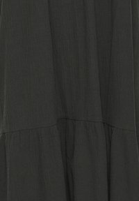 Tissu noir avec une couture froncée et un détail de surface texturé et froissé.