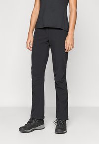 Calças de exterior pretas com um design ajustado, apresentando remendos nos joelhos e uma textura suave. Usadas com botas de caminhada escuras.