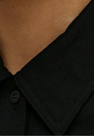 Col de chemise en coton noir avec un design plié, doté d'un bouton solide et d'un détail de couture visible le long des bords.