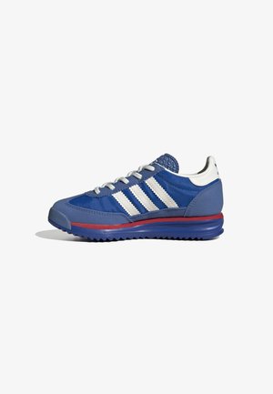 Scarpa sportiva blu con accenti grigi, design a tre strisce bianche, punta rotonda, upper testurizzato e una linea rossa sulla suola per un tocco di dettaglio in più.