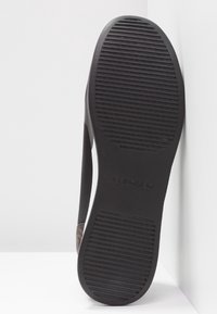 Svart sandal med en strukturerad gummisula, böjda remmar och en diskret logotyp på sidan. Slät ovandel med ett mönstrat mönster.