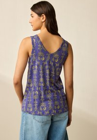 Top viola senza maniche con scollo a V e motivo geometrico dorato. Il tessuto appare leggero con una texture morbida. I bordi sono rifiniti con cura.