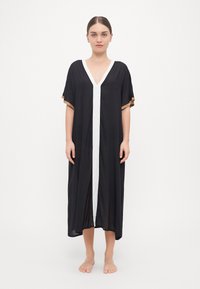Črn kaftan z V-izrezom, belim sprednjim delom in kratkimi rokavi, okrašenimi z zlatimi detajli. Lahkotna, spuščena tkanina, dolžina do tal.