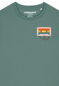Grünes Baumwoll-T-Shirt mit einem Kassettenband-Print in Orange, Blau und Gelb auf der linken Brustseite. Kurzärmliges Design.