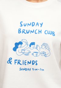 Τρία μπλε καρτούν άτομα απολαμβάνουν πρωινό με το κείμενο «Sunday Brunch Club & Friends Κυριακή 9 π.μ.-3 μ.μ.» πάνω σε λευκό ύφασμα.